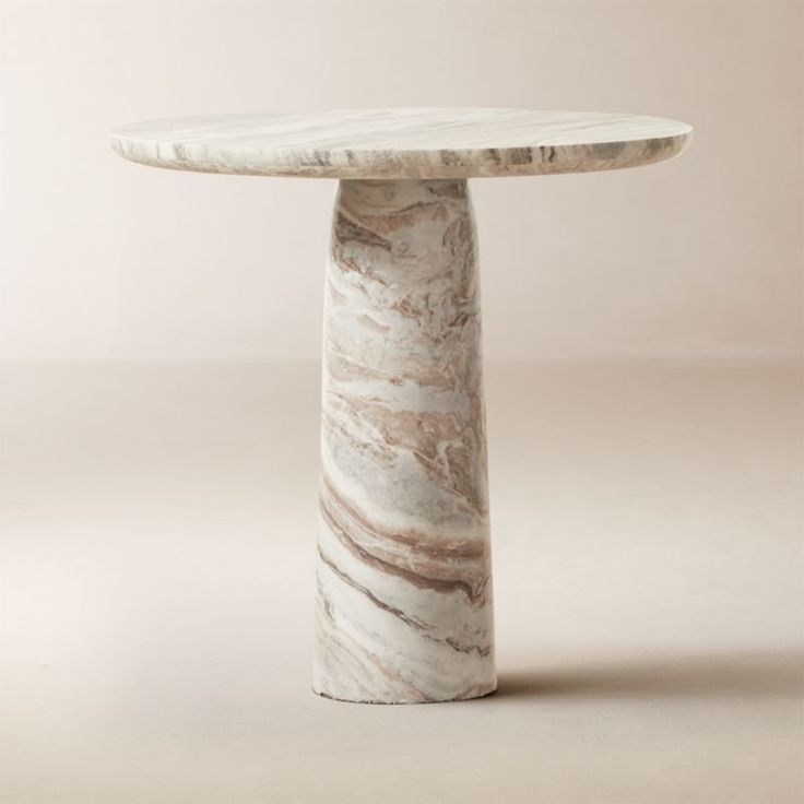 a white marble table sitting on top of a gray floor next to a pink wall