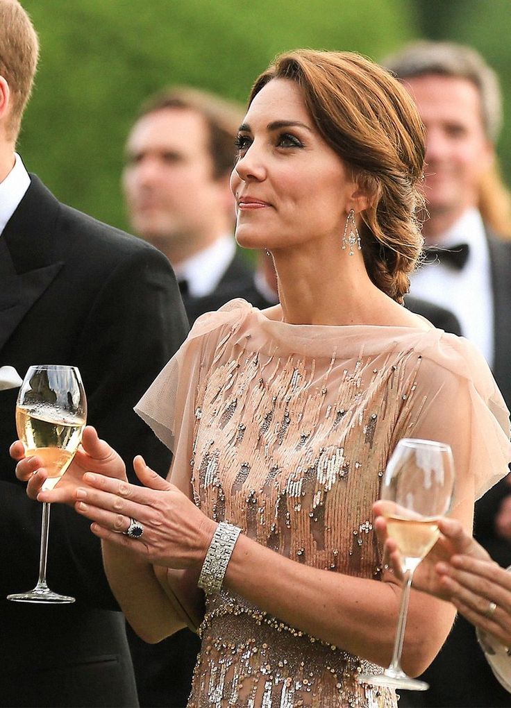 a man and woman holding wine glasses in front of other people wearing tuxedos