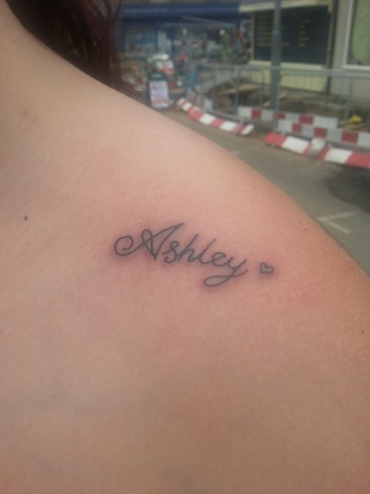 a woman with a tattoo on her shoulder that says, ashley in cursive writing