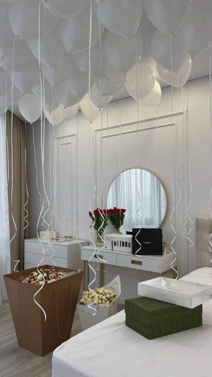 balloons are hanging from the ceiling above a bed in a room with white walls and flooring