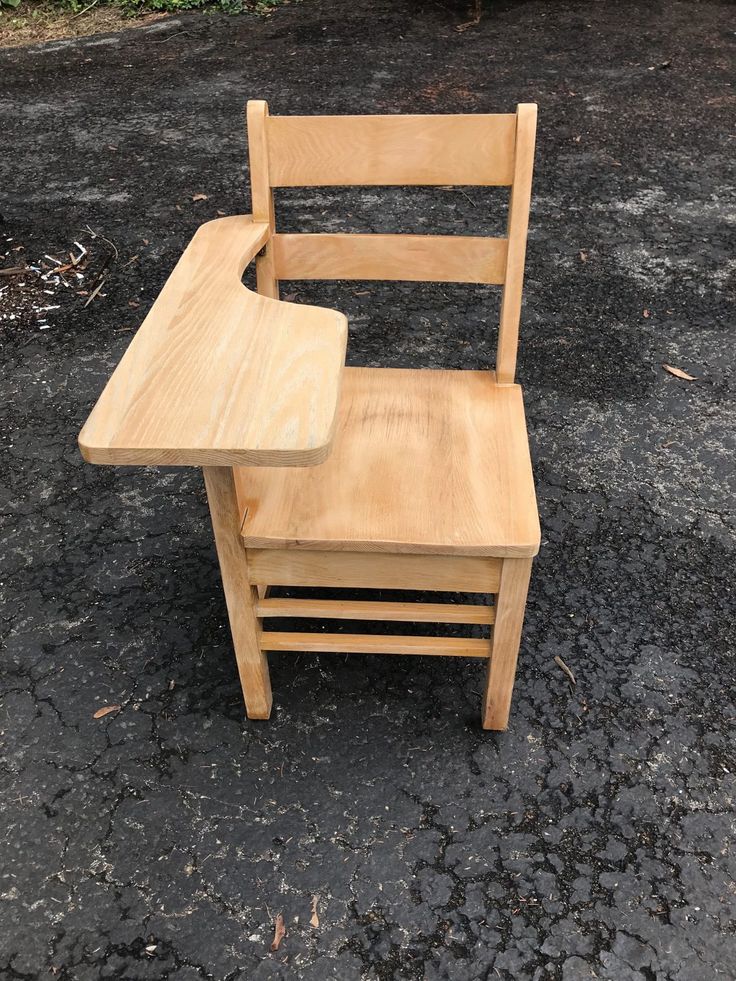 a wooden chair sitting on the ground next to a small table that is made out of wood