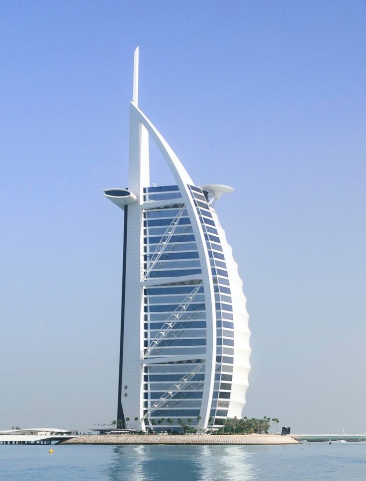 a very tall building sitting on top of the ocean next to a boat in the water