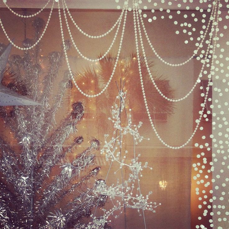 a white christmas tree sitting in front of a window with lights on the windowsill