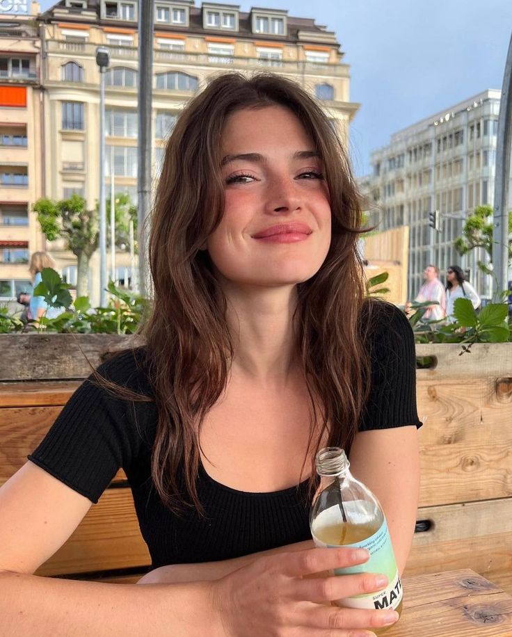 a woman sitting at a table with a bottle of water