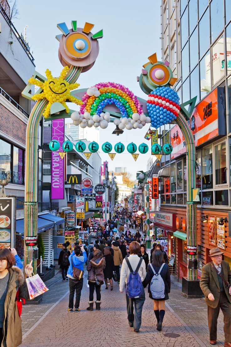 many people are walking down the street under an arch