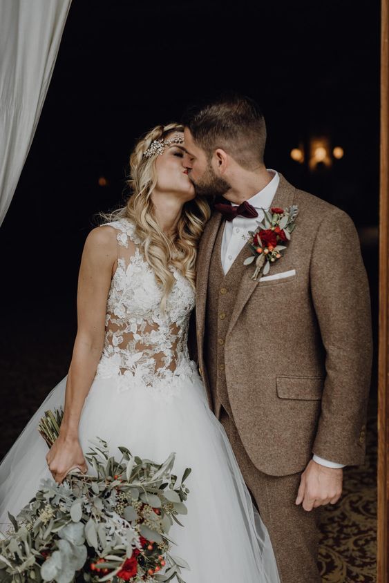 a bride and groom kissing in front of a window