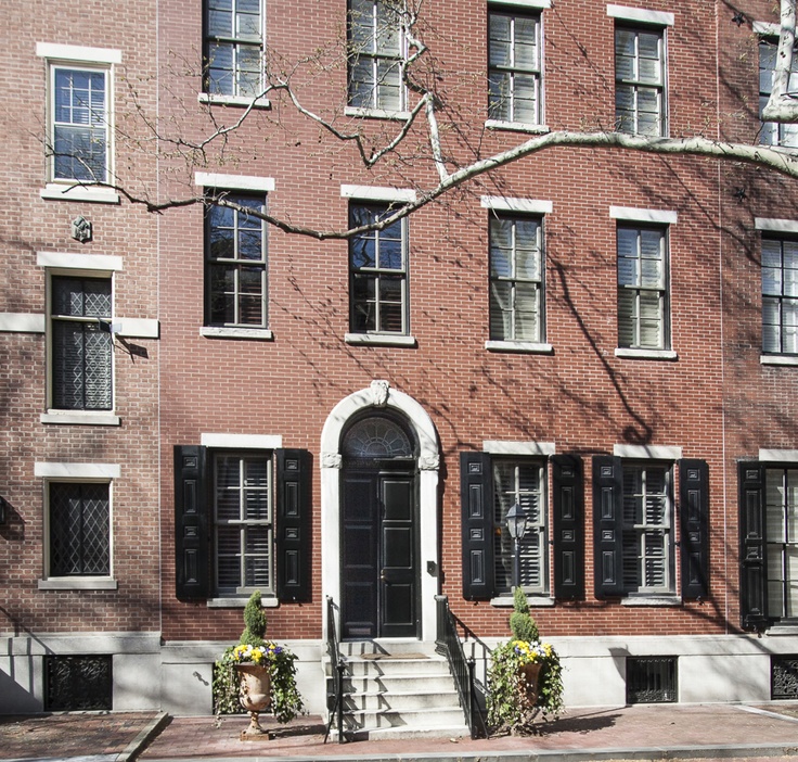 a red brick building with black shutters on the front door and steps leading up to it