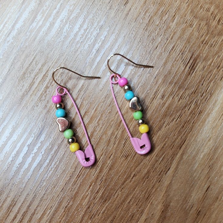 two pairs of pink and green beaded earrings sitting on top of a wooden table