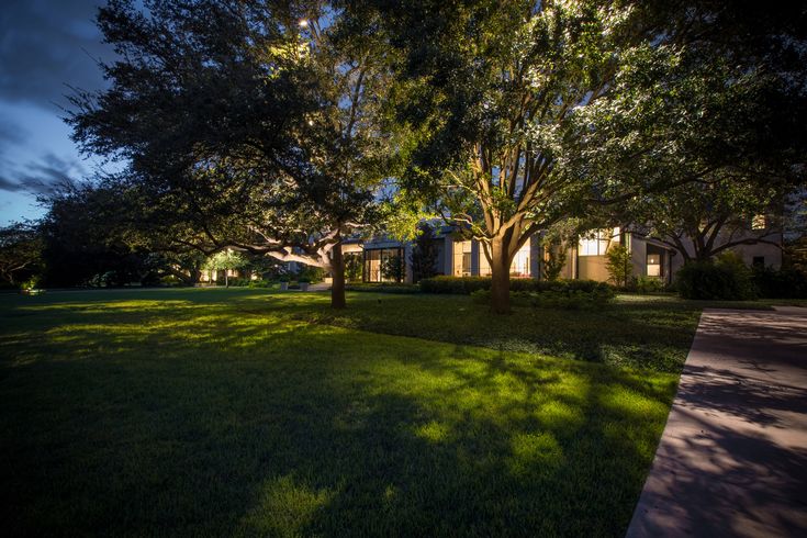 the house is lit up at night with bright lights on it's windows and trees