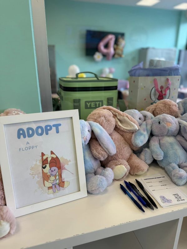 two stuffed animals sitting on top of a desk next to a sign and some pens