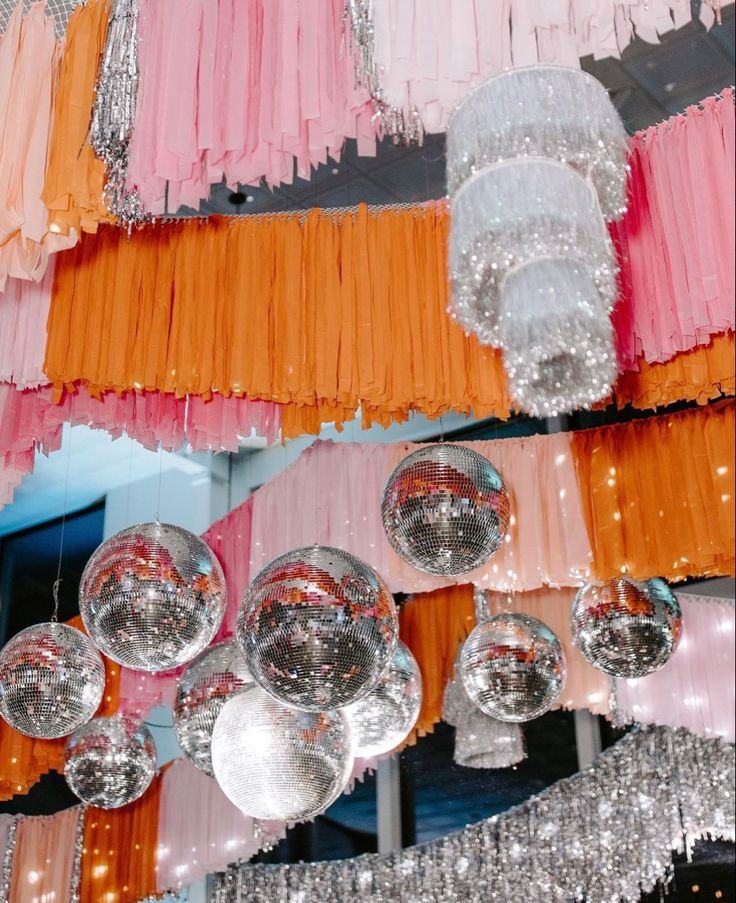 several chandeliers hanging from the ceiling in a room with pink and orange ribbons