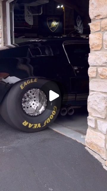 a black car parked in front of a garage with its tire on it's side