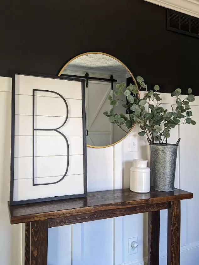 a table with a mirror, vase and plant on it