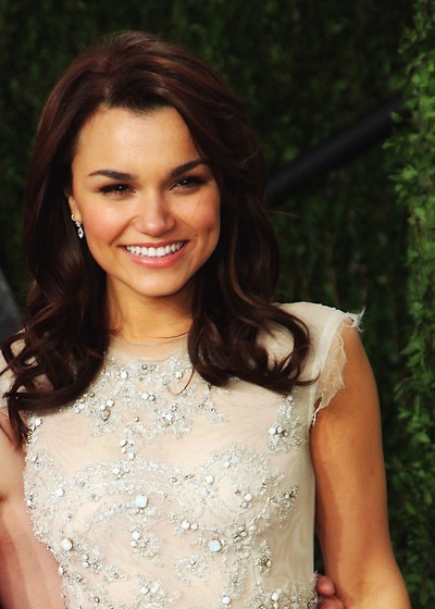 a woman in a white dress smiling at the camera