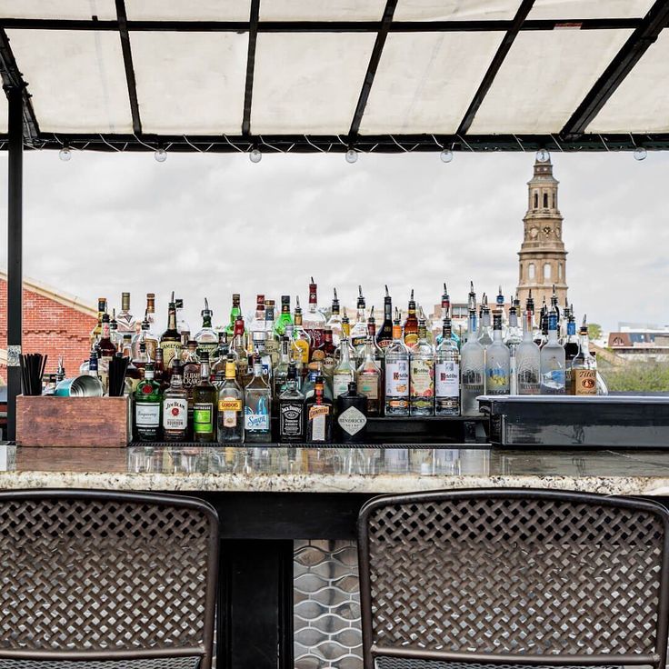 there are two chairs at the bar with many bottles on it and one is empty