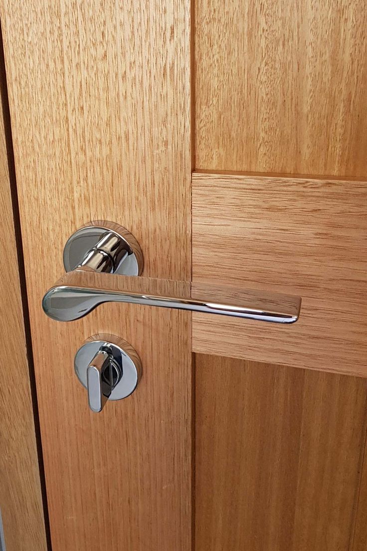 an open door with a metal handle on it's side and wood paneling