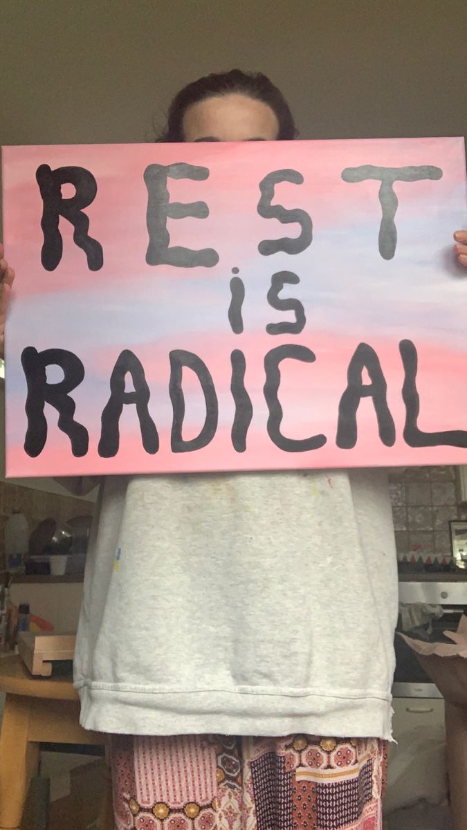 a person holding up a sign that says rest radical