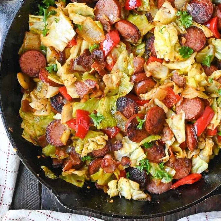 a skillet filled with sausage, cabbage and red peppers