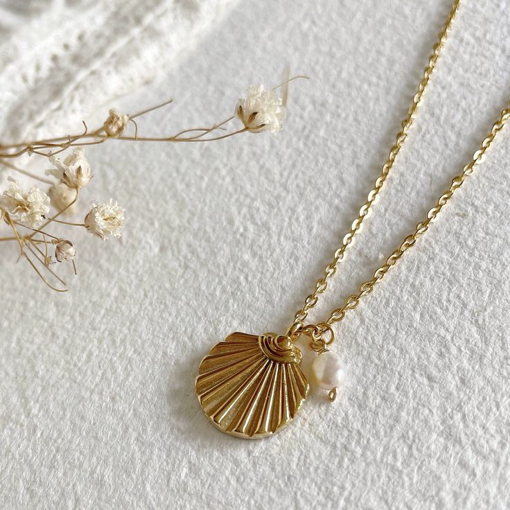 Stunning dainty pearl seashell necklace! This gold shell necklace is stunning on its own or layered with other necklaces for a powerful look.   The necklace is made of waterproof and hypoallergenic gold plated high quality stainless steel. It features a lovely chunky ribbed shell and a small freshwater pearl charm. If you prefer, you can move the pearl to the end of the chain and wear the necklace with just the shell pendant. To get your perfect fit, the necklace comes with an extender chain and Shell-shaped Pearl Charm Necklace, Shell-shaped Pearl Chain Necklace, Shell-shaped Pearl Charm Necklace For Gift, Pearl Chain Shell Necklace For Gift, Dainty Shell Necklaces Perfect As Gifts, Shell-shaped Pearl Charm Necklaces, Pearl Chain Shell Necklace As Gift, Dainty Shell-shaped Necklace With Pearl Charm, Pearl Necklace With Shell Shape For Gift