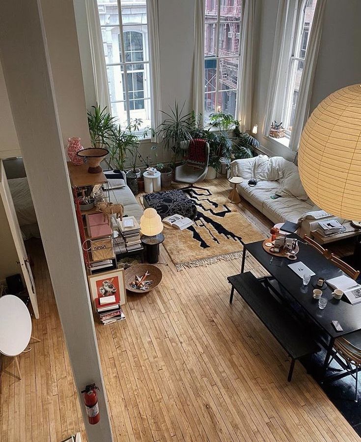 a living room filled with lots of furniture next to a tall white lamp on top of a hard wood floor