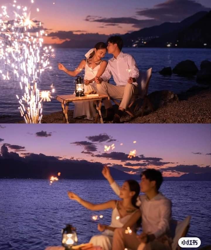 a couple sitting at a table with sparklers in their hands and on the beach