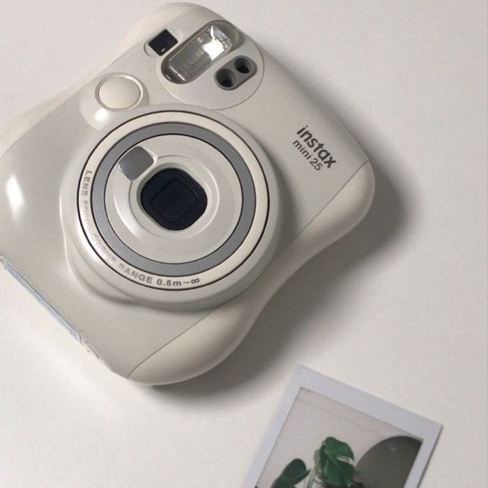 a white digital camera sitting on top of a table next to a polaroid print