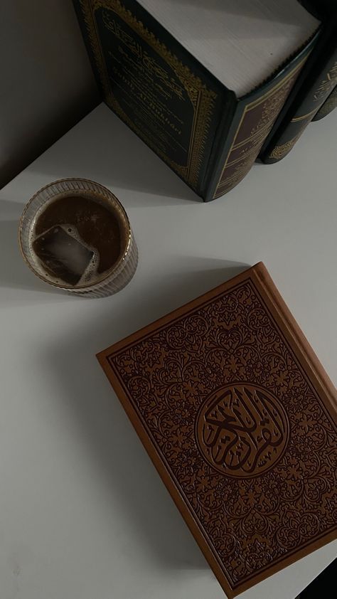 an open book sitting on top of a white table next to a bowl and cup