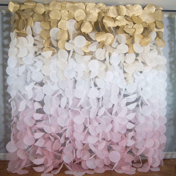 a gold and white curtain with pink flowers hanging from it's side on a wooden floor