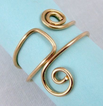 a gold plated ring on top of a light blue piece of paper with the letter s in it