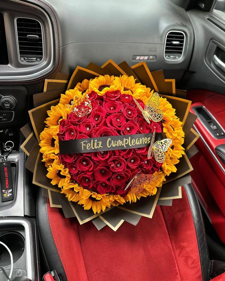 a bouquet of sunflowers and roses is sitting in the center console of a car