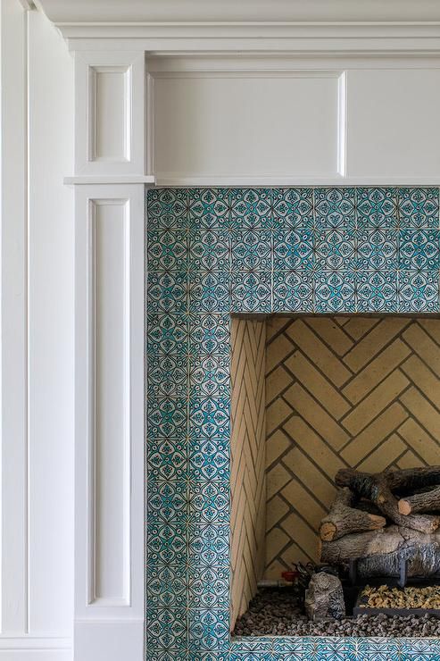 a fireplace with blue and white tiles on the wall next to logs in front of it