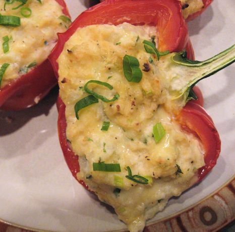 two stuffed red peppers with cheese and green onions