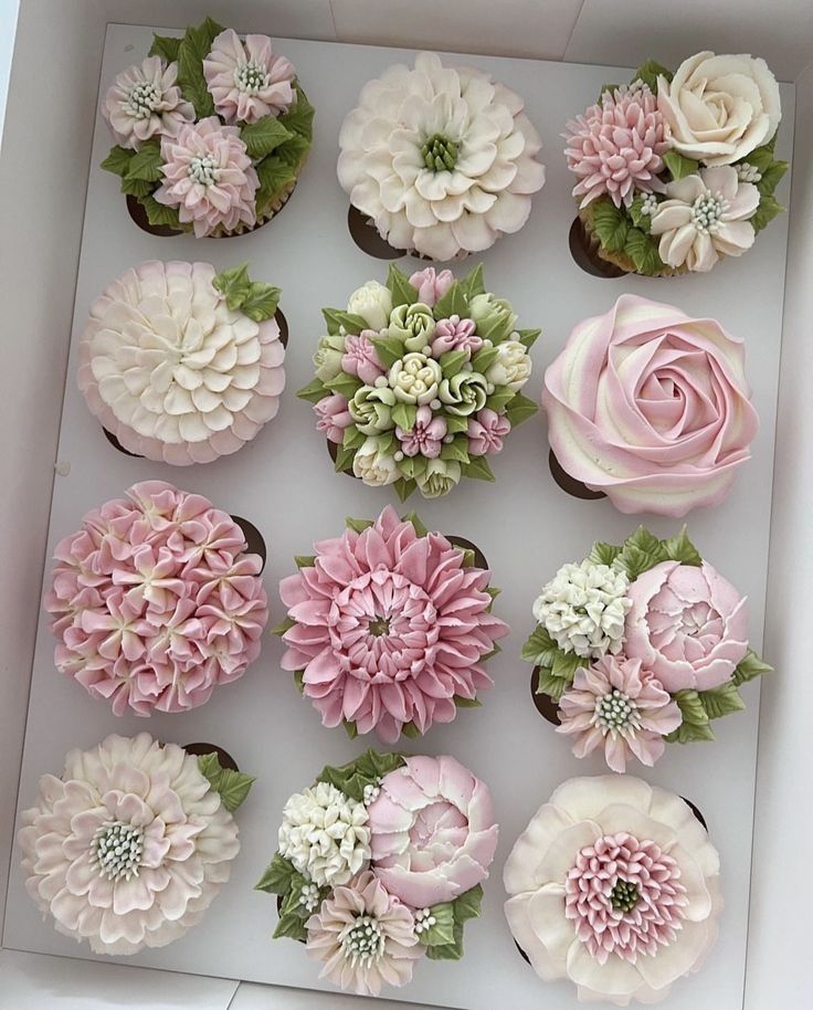 cupcakes decorated with pink and white flowers in a box