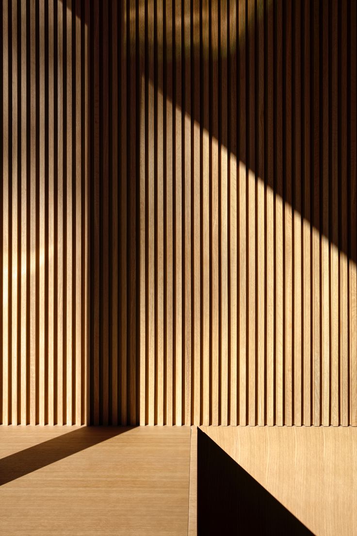 an empty room with wooden slats on the wall and flooring in front of it