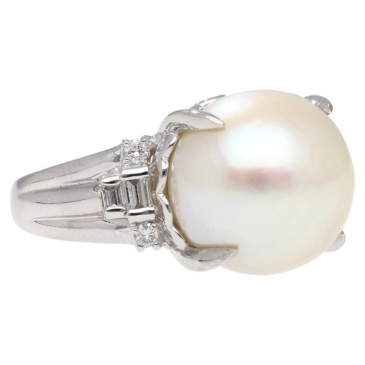 15mm South Sea Pearl and Diamond Platinum 900 Cocktail Ring. Featuring a lustrous 15mm south sea white pearl center stone, secured in a prong setting. The pearl is paired with 4 round cut and 4 baguette cut natural diamonds. The pearl is secured in a basket setting with a heart shape motif, and half bezel set diamonds and share weight of 0.46 carats. The ring is crafted from platinum 900. The pearl has phenomenal uniformity and symmetry. Set in a platinum 900 that offers supreme durability and s Formal White Pearl Ring, White Akoya Pearl Timeless Ring, Timeless White Akoya Pearl Ring, White Pearl Drop Ring For Formal Occasions, Classic White Pearl Ring With Drop Detail, Classic White Pearl Ring, Luxury White Rings With Pearl Drop, Classic White Pearl Ring With Diamond Accents, Timeless Akoya Pearl Ring For Formal Occasions