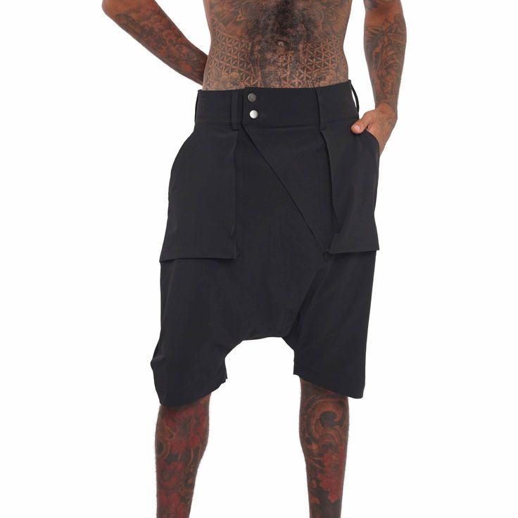 Breathable, super lightweight, water resistant active fabric meets tailored structure in these black techwear shorts. The Dublin Mens Drop Crotch Shorts have a streetwear aesthetic but function as a multi purpose garment. Comfortable enough to lounge in and suitable to swim in; the perfect shorts for travelers and spontaneous souls. FEATURES: Harem style: low dropped crotch Long length, hits just below the knee Four pockets, two with zippers, one of which is hidden Belt loops Diagonal zip fly Ma Alternative Black Streetwear Shorts, Alternative Black Shorts For Streetwear, Functional Black Bottoms With Built-in Shorts, Alternative Style Black Bottoms For Summer, Black Alternative Style Bottoms For Summer, Alternative Style Black Summer Bottoms, Black Fitted Alternative Style Shorts, Functional Baggy Black Bottoms, Functional Black Baggy Bottoms