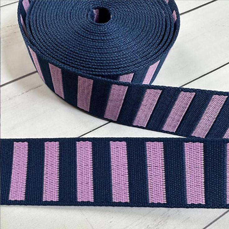 a roll of blue and pink striped ribbon sitting on top of a white wooden floor