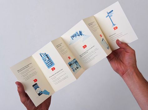 a person is holding up three folded brochures with pictures on the front and back