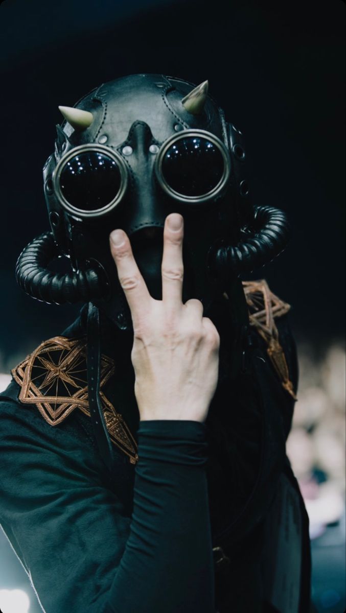 a person wearing a gas mask making the v sign with their hand and holding up two fingers