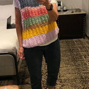 a woman is taking a selfie with her cell phone while wearing a multicolored sweater