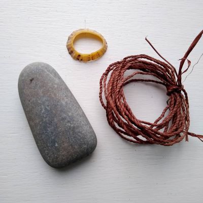 a rock, rope and ring sitting on top of a white surface