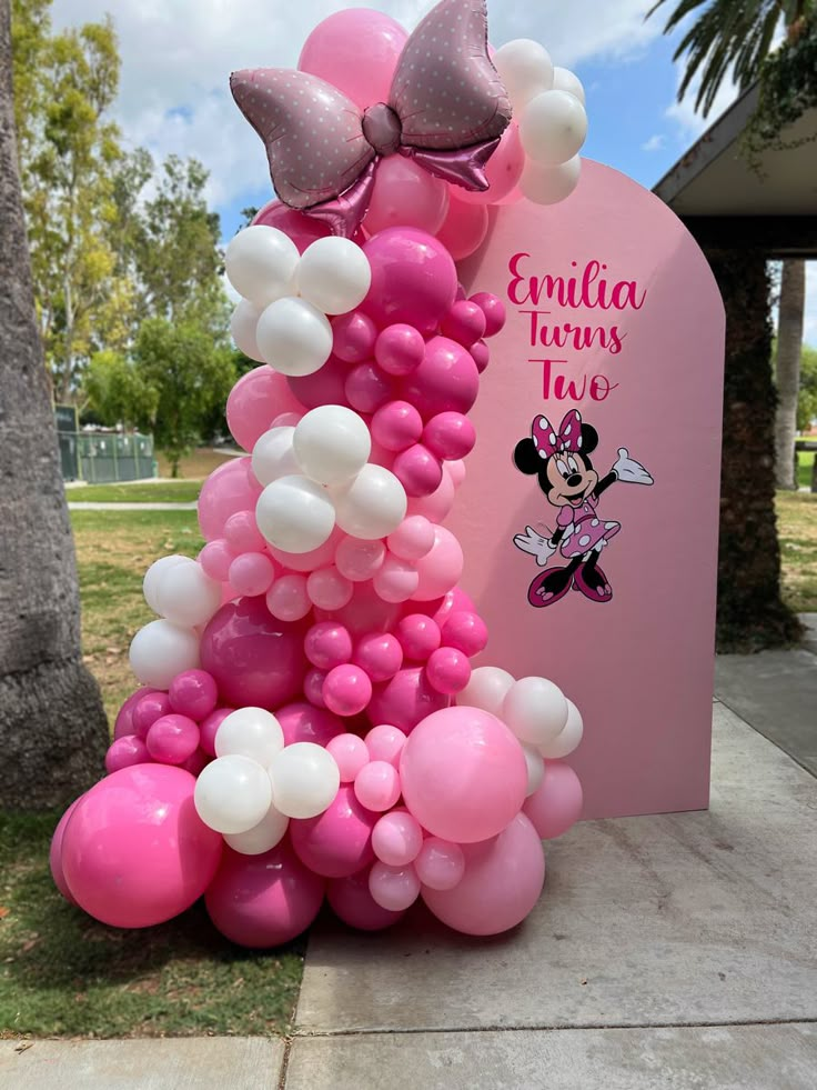 a pink and white balloon tower with minnie mouse balloons