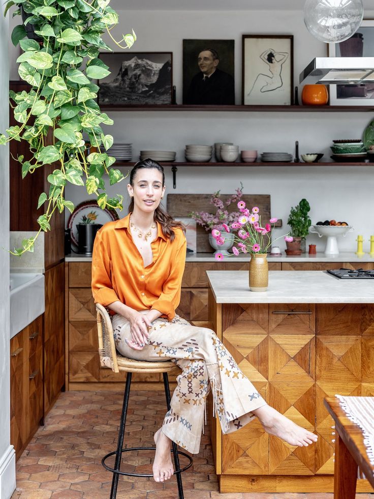 a woman sitting on a chair in front of a kitchen counter with potted plants