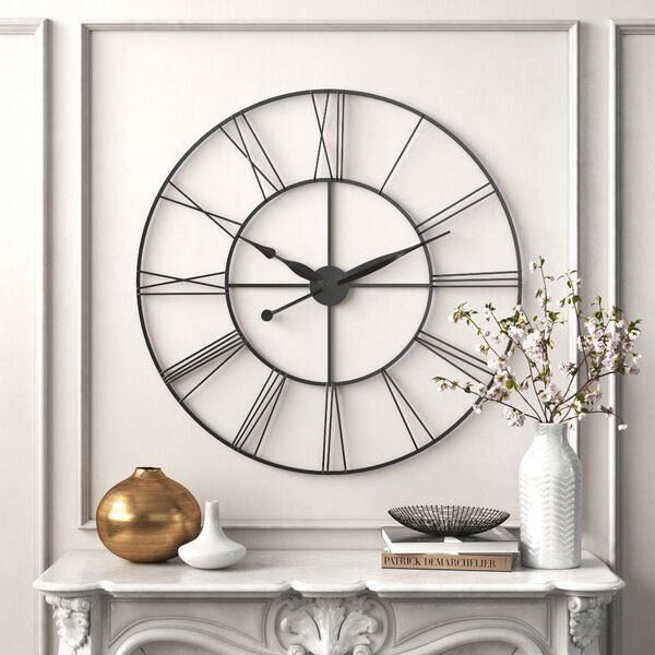 a large clock mounted to the side of a wall above a mantle with vases on it