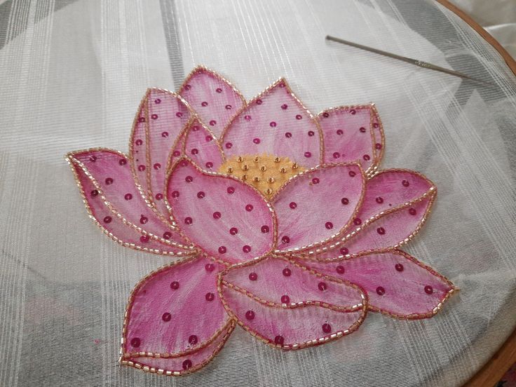 a close up of a pink flower on a piece of cloth with pins in it