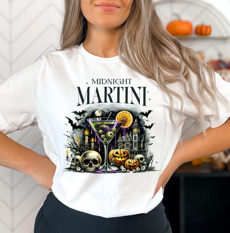 This eerie yet stylish Midnight Martini t-shirt is the ultimate Halloween party staple! The design features a spooky martini glass with eyeball-shaped olives, set against a haunted house backdrop that brings the perfect mix of mystery and fright. On either side of the glass, detailed skeleton skulls and pumpkins add an extra touch of spooky fun, making it ideal for anyone who loves a Halloween twist on classic cocktails. Whether you're heading to a haunted happy hour or just embracing the Halloween spirit, this shirt is the perfect way to sip in style! ❤  FEATURES  ❤ * Premium Quality: Made with 100% Airlume combed and ring-spun cotton for a soft and comfortable fit. * Versatile Sizes & Colors: Available in a variety of sizes and colors to suit your style. * USA Made: All orders are printe Halloween Party Tops With Letter Print, Halloween Party Letter Print Tops, White Halloween Party Tops, White Halloween Party Top, Halloween Party Graphic T-shirt, Halloween Party Graphic Print T-shirt, Fitted Graphic Print T-shirt For Costume Party, Spooky Drinks, Halloween Cocktail