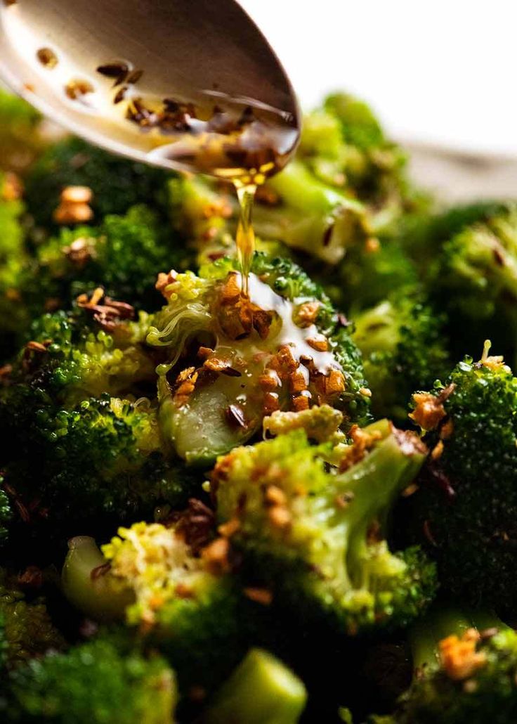 broccoli florets are being drizzled with mustard and seasoning