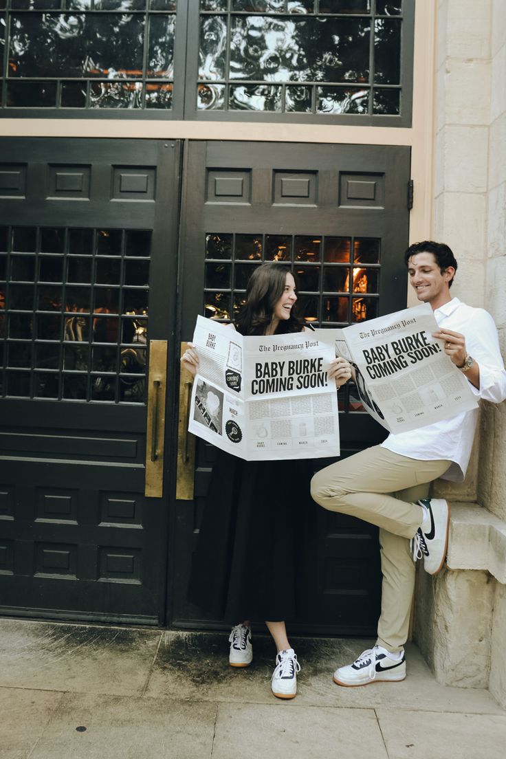 a man and woman sitting on the side of a building while holding up newspapers