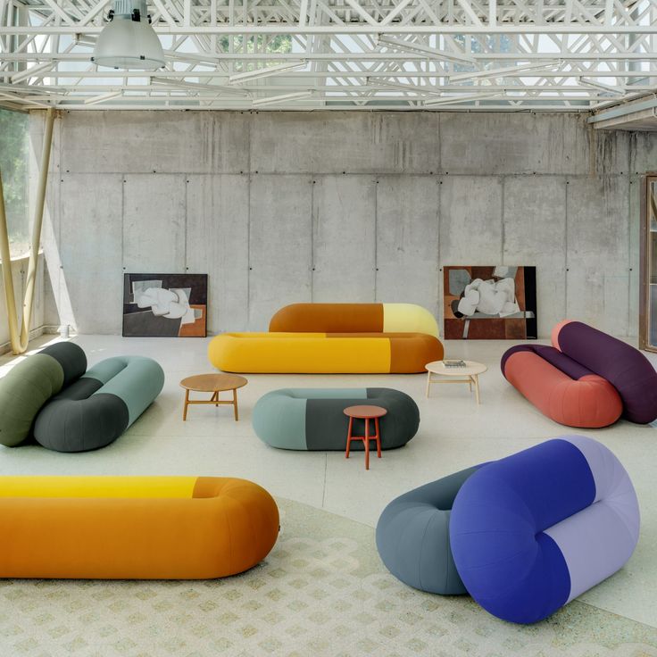 a room with several different colored couches and chairs on the floor next to each other