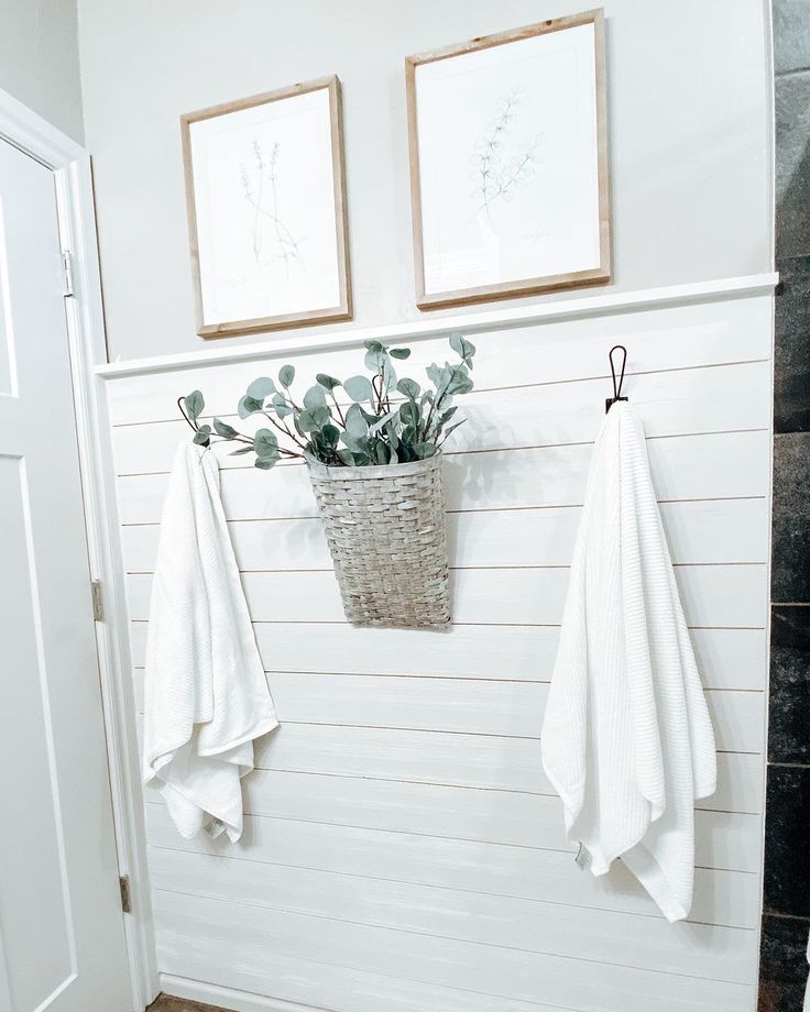 two white towels hanging on the wall next to a basket with plants